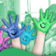 Mehrere bunt bemalte Hände vor grünem Hintergrund