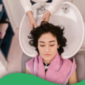Dunkelhaarige Frau welcher die Haare beim Friseur im Waschbecken gewaschen werden
