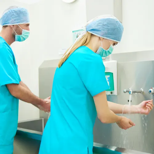 Pflegekräfte in türkiser Kleidung desinfizieren ihr Hände