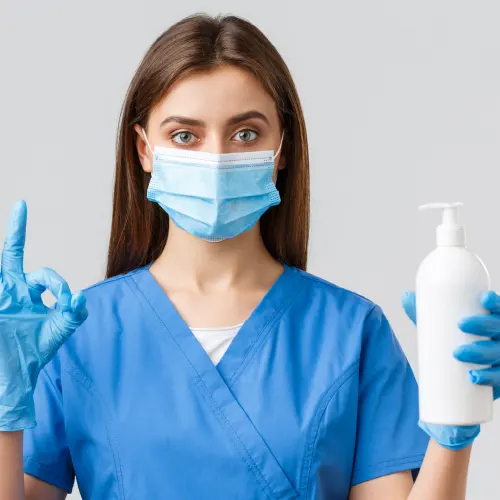 Krankenschwester mit Mundschutz hält Desinfektionsspender